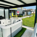 Extérieur du showroom Extend à Lescure d'Albigeois, mettant en avant des jacuzzis de la marque BE SPA sous une pergola moderne. L'environnement est bien aménagé avec un gazon artificiel et offre une vue sur le magasin en arrière-plan, soulignant une ambiance accueillante et professionnelle pour la présentation de spas.