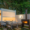 Espace extérieur élégant du magasin Pain Concept et Design Paysage à Batz-sur-Mer, mettant en vedette un spa BE SPA sous un abri moderne avec toit ouvrant. La scène inclut des meubles de jardin confortables et un foyer extérieur en fonction, créant une ambiance accueillante et relaxante. L'ensemble est entouré de murs blancs et d'arbres verdoyants, offrant intimité et connexion avec la nature.