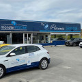 Façade du magasin Piscines Sérénité Mondial Piscine à Creysse, avec un grand panneau bleu portant les logos de Mondial Piscine et Piscines Sérénité. Des voitures stationnées devant le bâtiment sur un parking spacieux reflètent une journée d'activité. L'entrée visible du magasin invite les clients à découvrir une gamme de produits de spa BE SPA et d'accessoires de piscine.